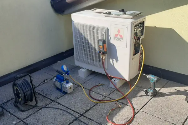 Tecnico specializzato idraulico esegue manutenzione e ricarica gas su unità esterna condizionatore